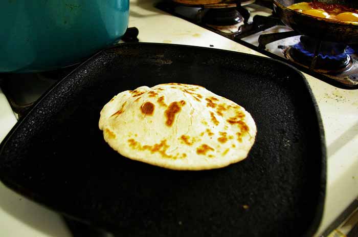 After Pressing Into A Disk In a Tortilla Press, Place On The Grill. Tip: Press Down The Center  To Allow for a Bubble In The Interior.