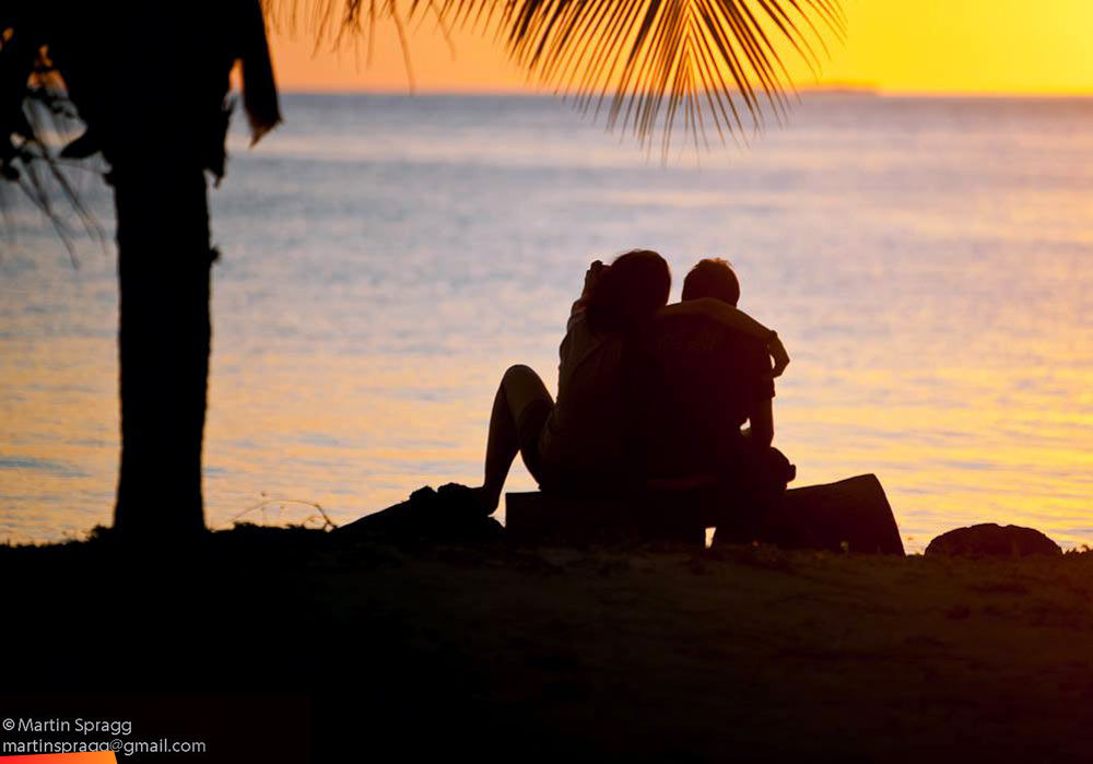 Couple on the beach at South Water Caye watching the sunset