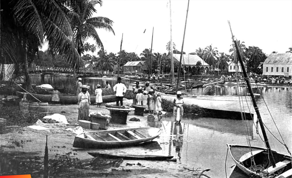 Lots of folks among lots of boats along the shore in Dangriga, 1911