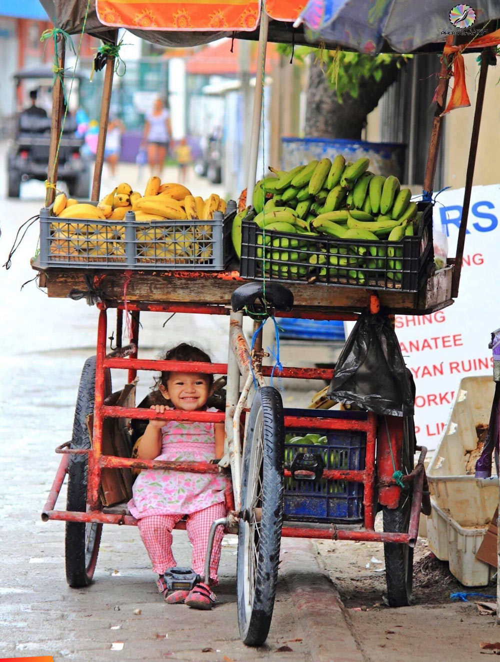 Little girl on the bottom of a fruit vendors cart in San Pedro, super cute