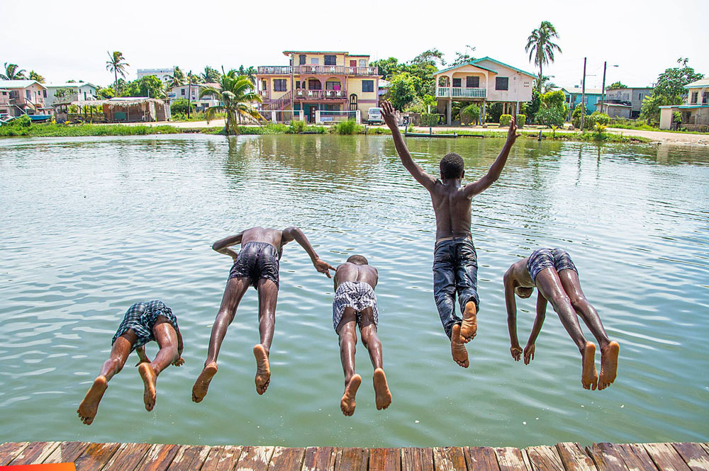Five boys diving off a pier in Dangriga, 2015