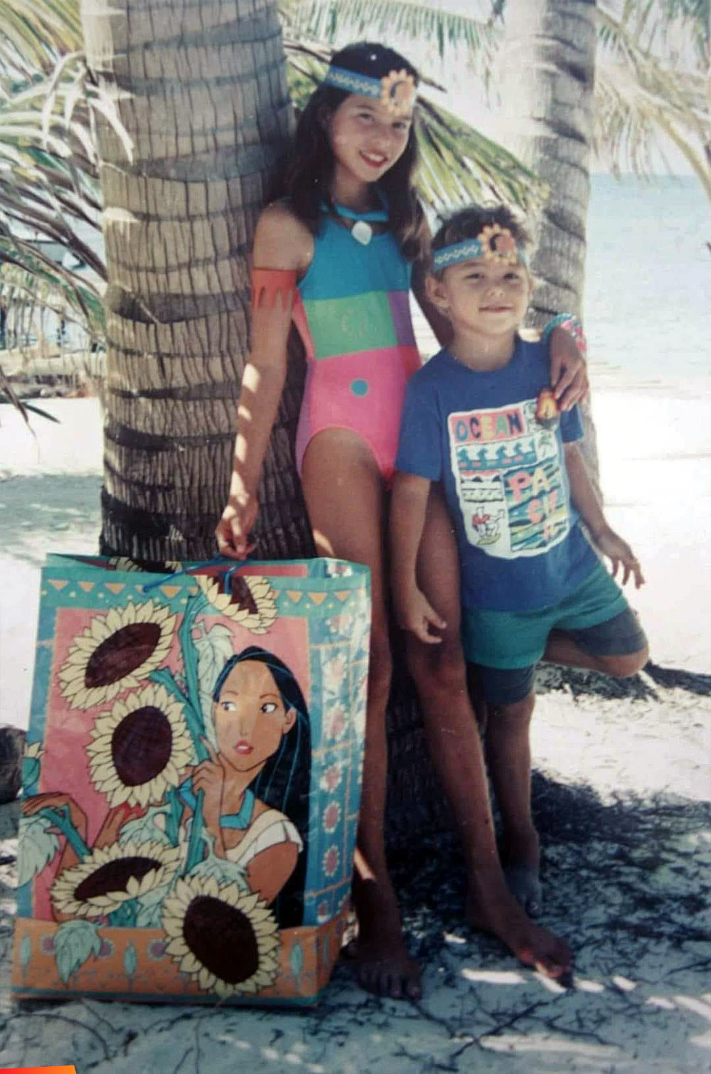 Melody and Dennis Wolfe II leaning on a palm tree, long ago when they were children