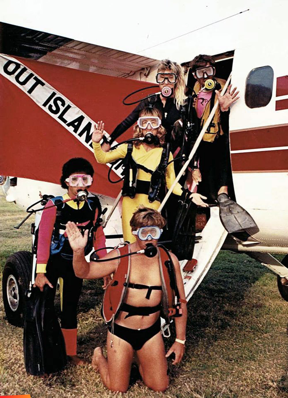 Ray Bowers, Linda Carter, Vicky Showler, Bruce Johnston, and Charlene Woods of Out Island Divers posing outside a Tropic Air plane, wearing scuba gear! 1990 or earlier