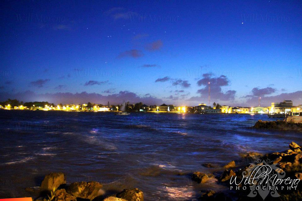 Belize City at night is so beautiful with the coastline lit, reflections in the water and stars in the sky.