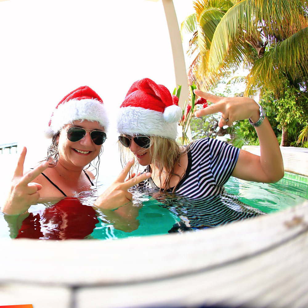 Sandra van Noord and Olivera Rusu showing Christmas Cheer in a small infinity pool at Cayo Espanto