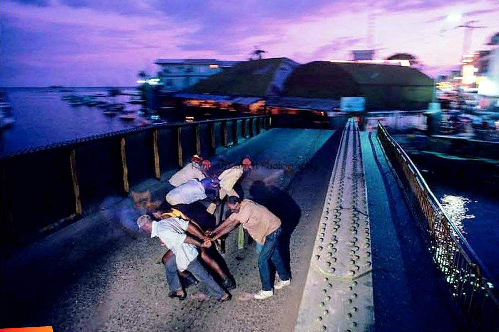 Swinging the bridge after dark. A rare picture of the old Belize City market lit up at night