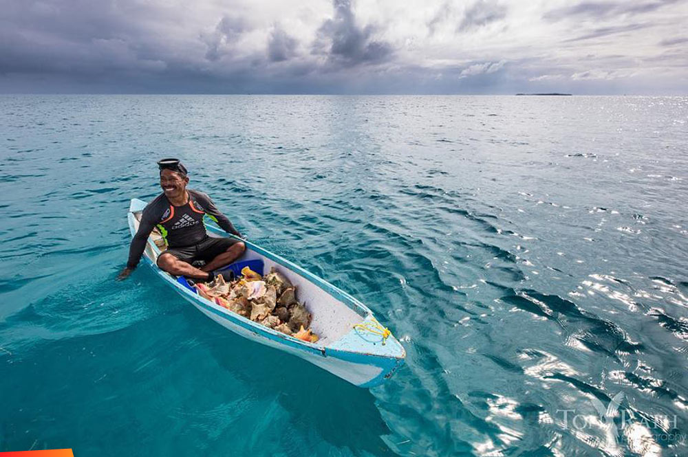 Fisherman in his boat with his conch catch
