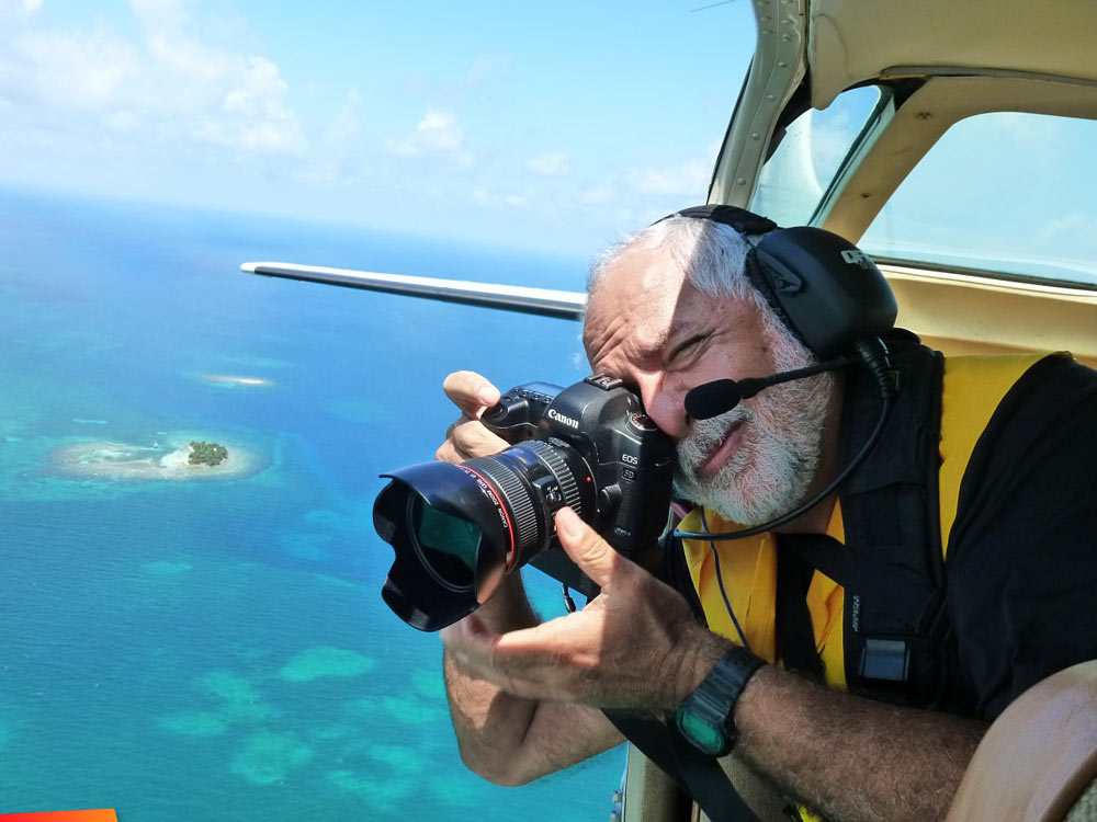 Tony Rath shooting photographs out the door of a plane...