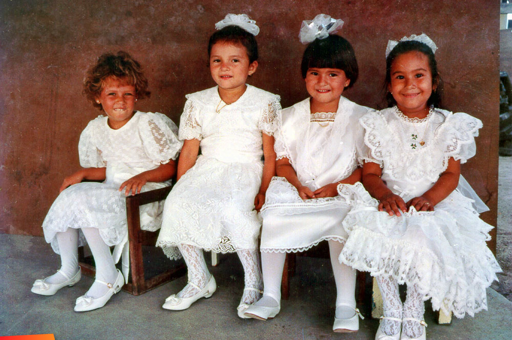 Four young girls getting ready for a pre-school graduation, 1980's